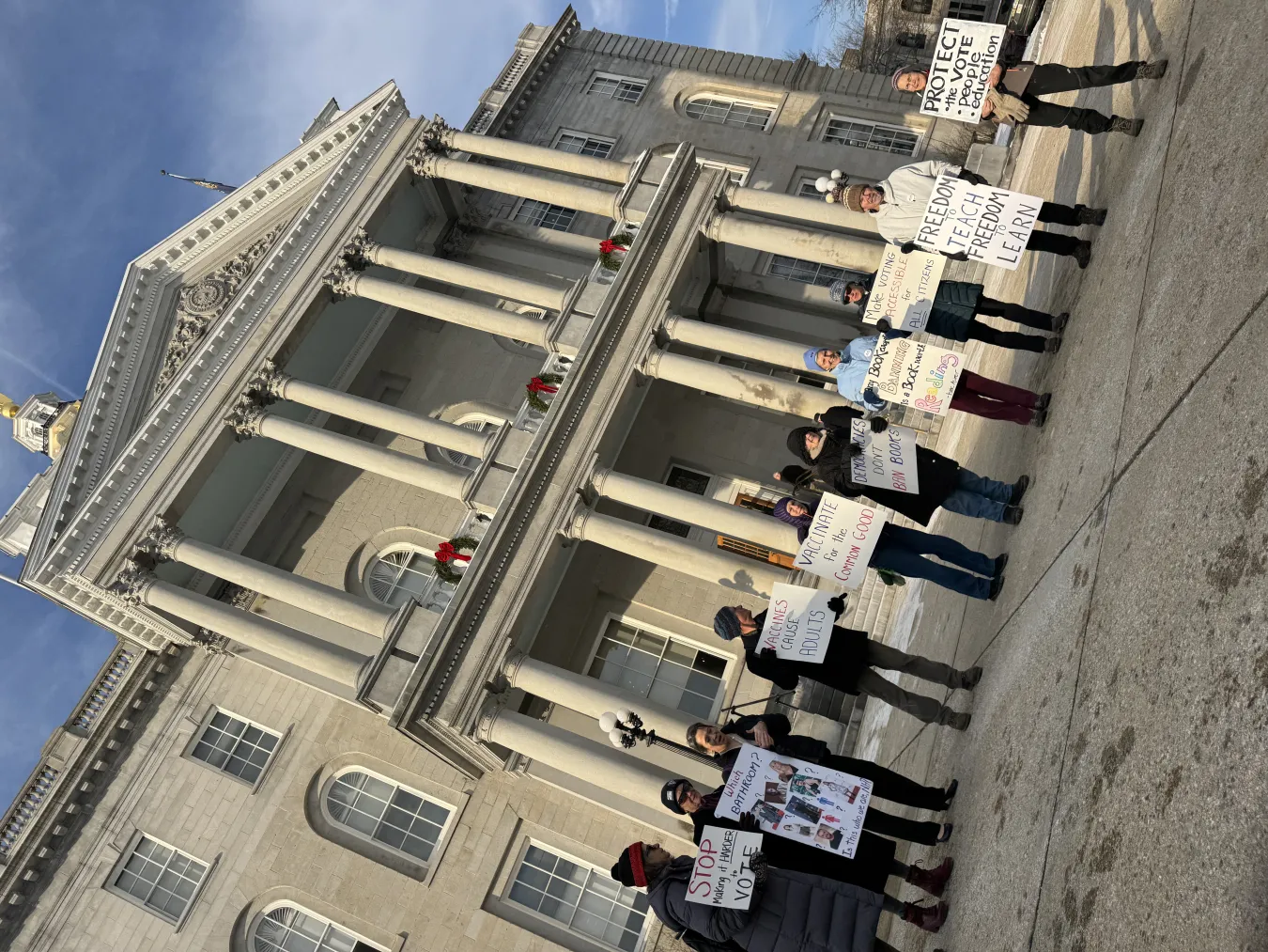 Advocates gather with protest signs outside of the New Hampshire State House.