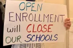 A sign reads "Open Enrollment will Close Our Schools"