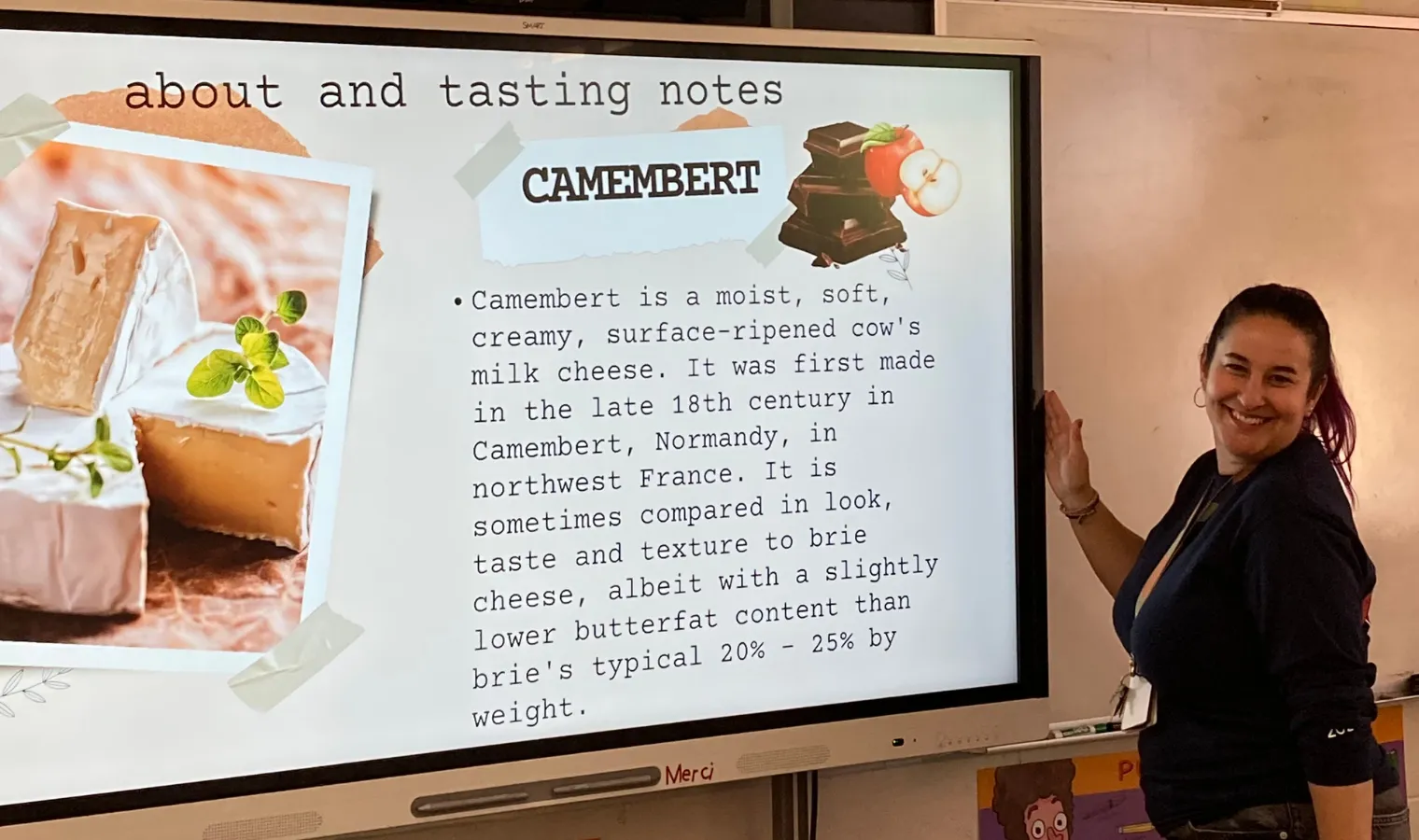 An image of Rebecca Fortgang in front of a classroom white board displaying information about French cheeses.