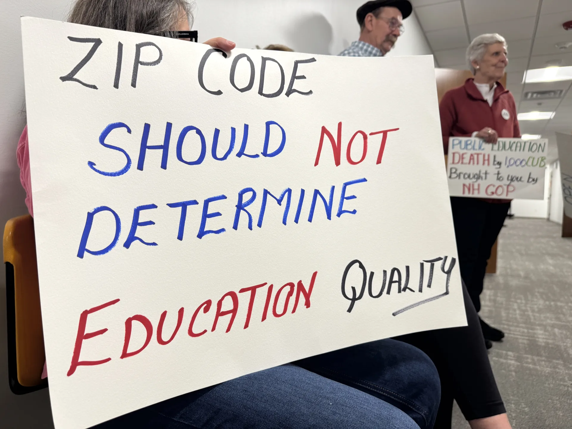 A sign reads: Zip code should not determine education quality. 