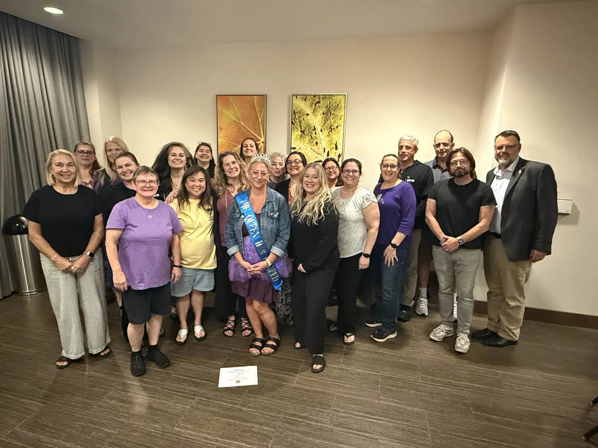 The 2026 New Hampshire delegates to the NEA Representative Assembly pose for a group photo. NEA-NH President stands front and center with a purple tutu and a sash that reads "The queen has retired".