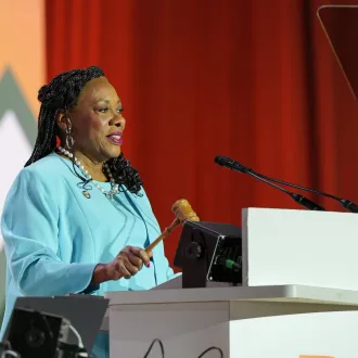 An image of NEA President Becky Pringle holding a gavel at a podium during the 2026 NEA RA