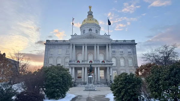 An image of the New Hampshire State House with snow on the ground and a sunset in the background.