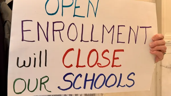 A sign reads "Open Enrollment will Close Our Schools"