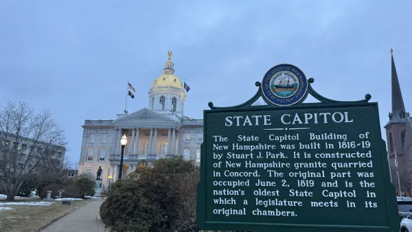 The New Hampshire State Capitol historical sign in the foreground at dusk; the New Hampshire State House in the background.